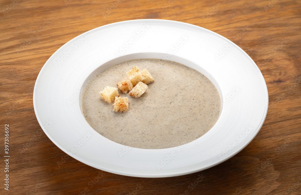 Mushroom soup puree with croutons and mushrooms on a wooden table