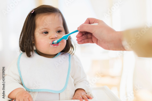 Hispanic mother feeding toddler in high chair