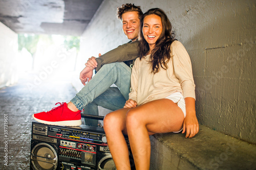 Caucasian couple listening to boom box in tunnel