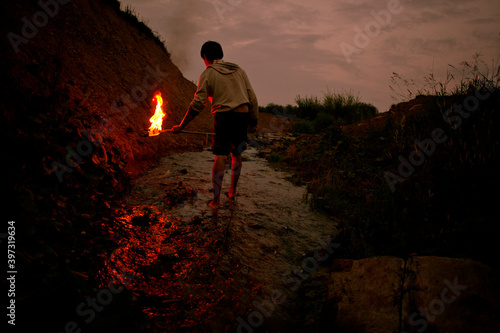 Mari man holding torch in rural creek
