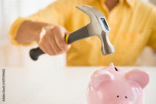 Close up of mixed race man holding hammer over piggy bank