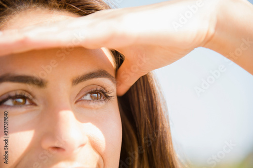 Close up of Caucasian woman shielding eyes from sun photo