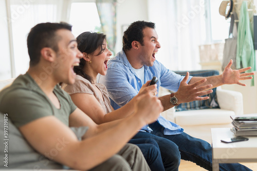Hispanic friends cheering at television in living room