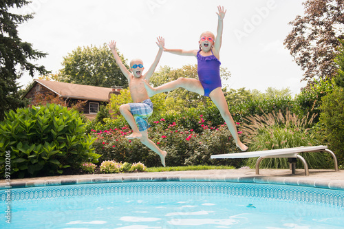 Caucasian children jumping into swimming pool photo