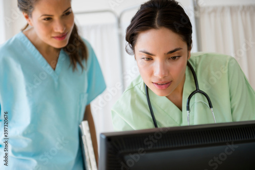 Hispanic nurses working together on computer at hospital