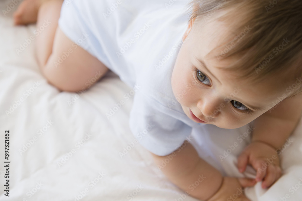 Close up of mixed race baby crawling on bed Close up of mixed race baby crawling on bed