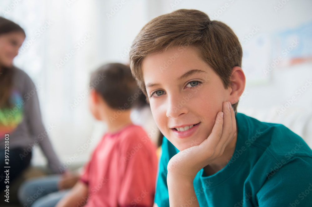 Smiling boy resting chin in hand in living room Smiling boy resting chin in hand in living room