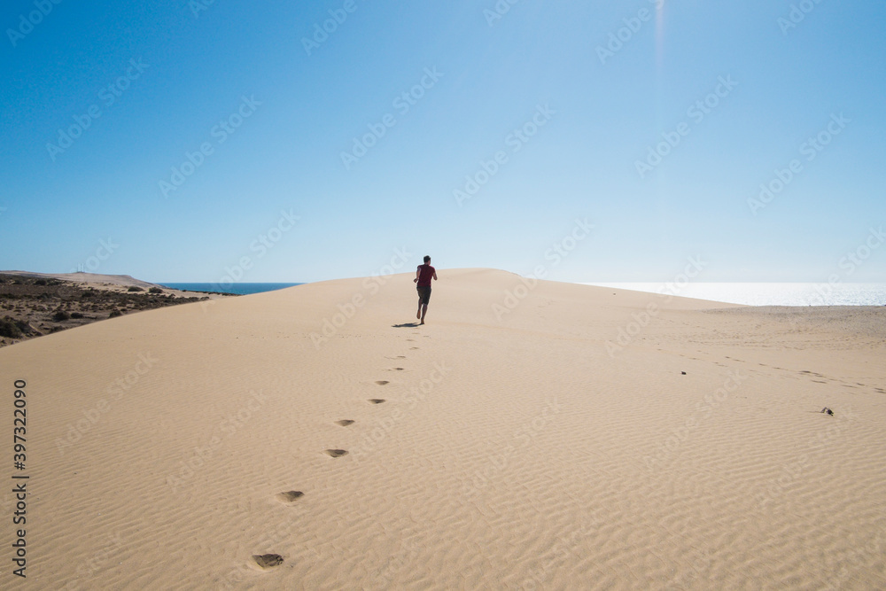 Caucasian teenage boy running on sand dune Caucasian teenage boy running on sand dune