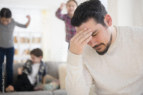 Stressed Caucasian father with shouting children in living room photo