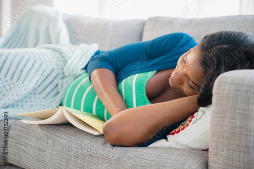 Black pregnant woman napping on sofa