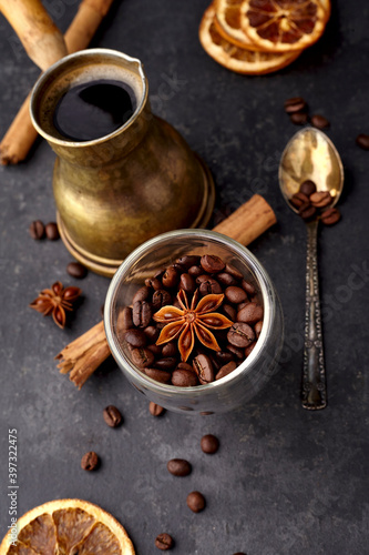 Coffee with coffee beans, anise, dry orange and cinnamon on black background. Coffee with spice. Top view.