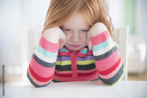 Caucasian girl crying at table photo