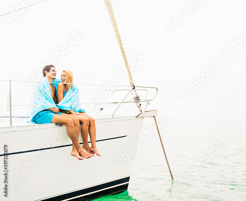 Couple wrapped in towels on deck of sailboat photo