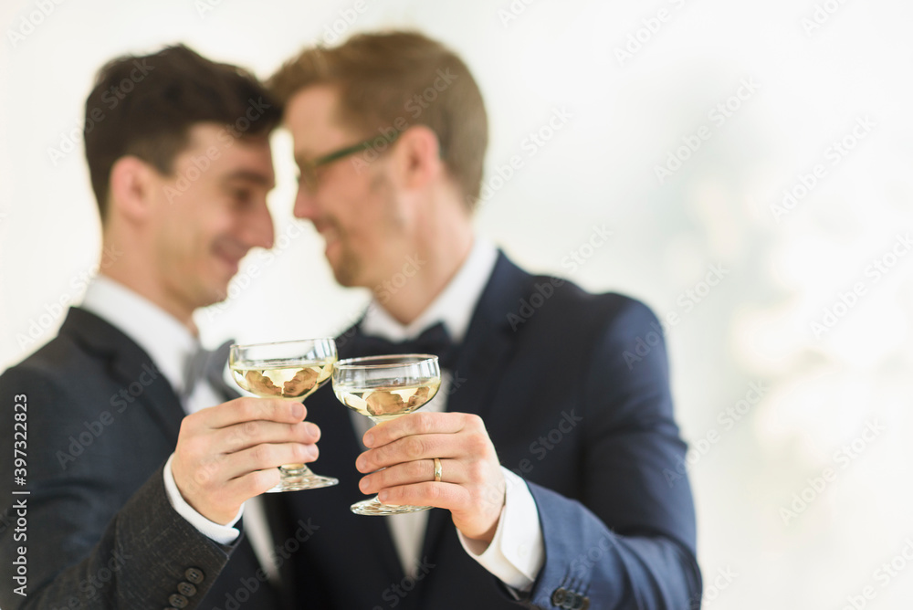 Caucasian gay grooms toasting with champagne at wedding Caucasian gay grooms toasting with champagne at wedding