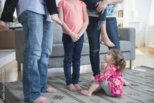 Caucasian girl sitting under family in living room photo