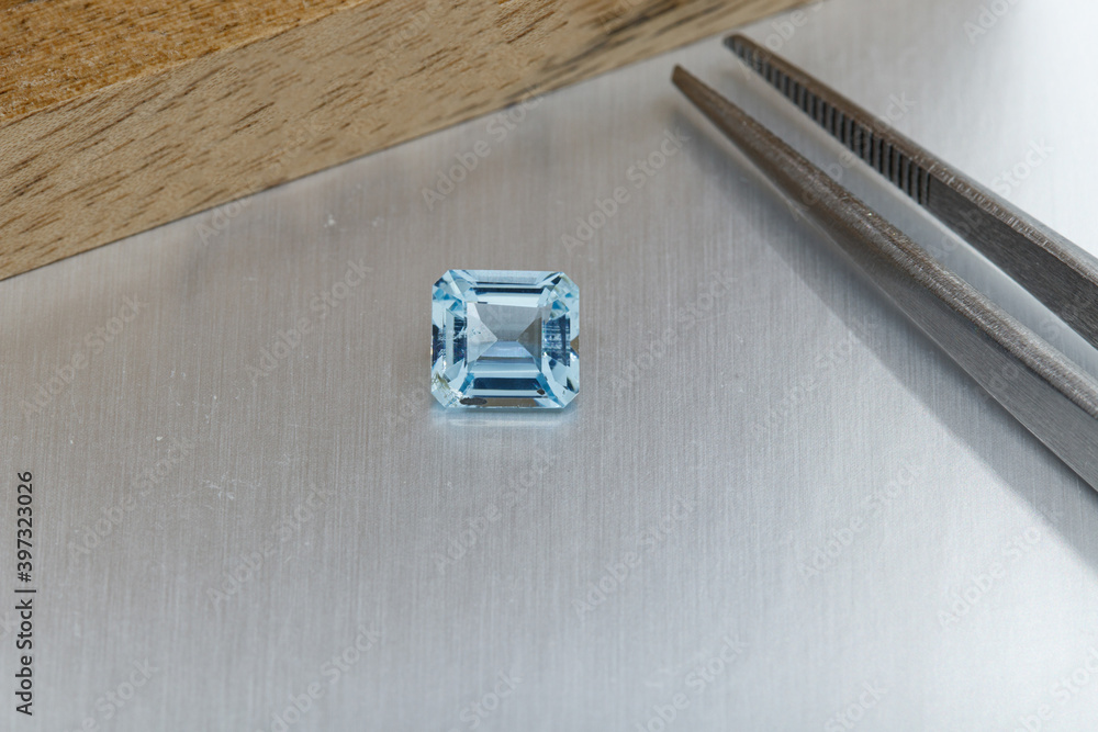 macro mineral faceted stone aquamarine with tweezers on a gray background macro mineral faceted stone aquamarine with tweezers on a gray background