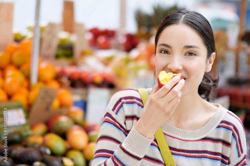 Hispanic woman eating fruit at farmers market Hispanic woman eating fruit at farmers market