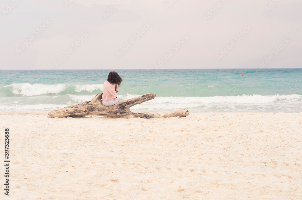 Woman sunbathing on driftwood log on beach Woman sunbathing on driftwood log on beach