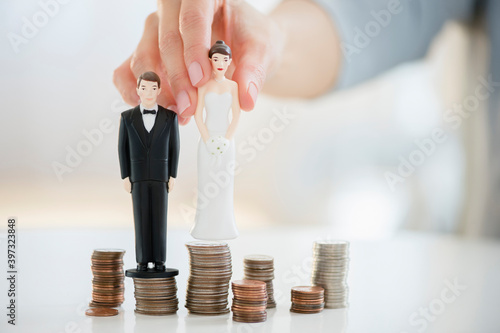Mixed race woman balancing bride and groom statues on coin stacks