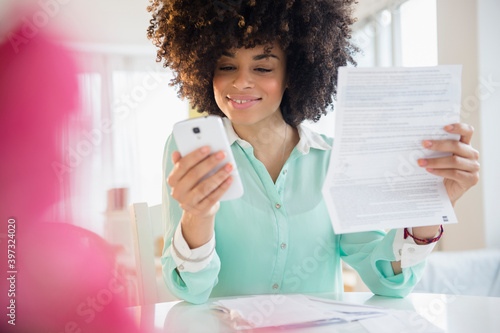 Mixed race woman paying bill with cell phone photo