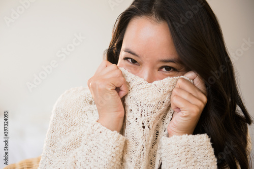 Chinese woman peeking over collar of sweater photo