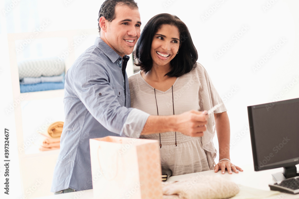 Hispanic couple paying at register Hispanic couple paying at register