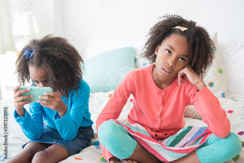Bored mixed race girl sitting on bed