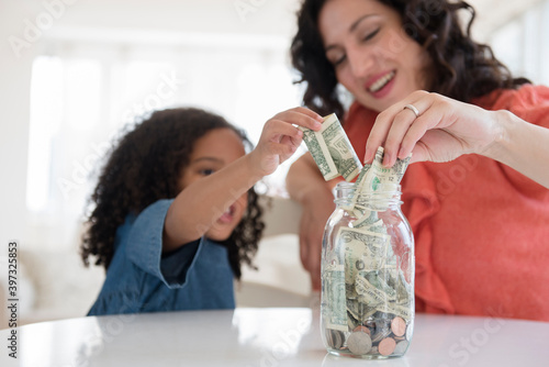 Mother and daughter saving money in jar photo