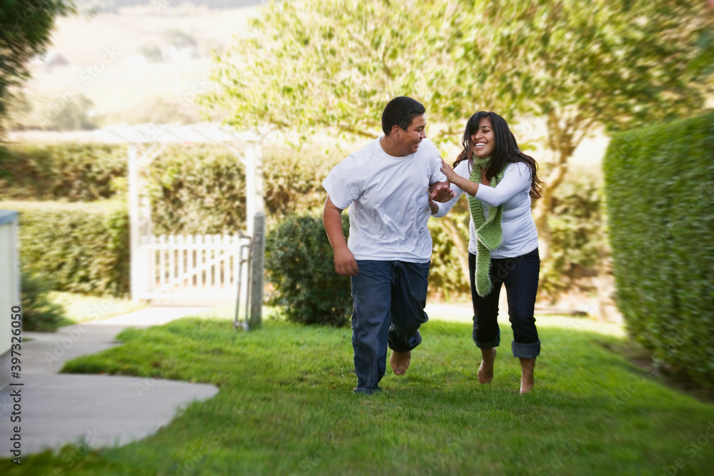 Hispanic brother and sister running on grass