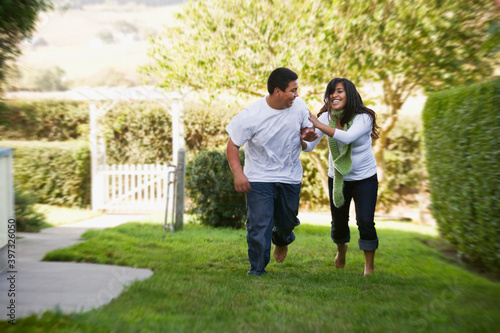 Hispanic brother and sister running on grass photo