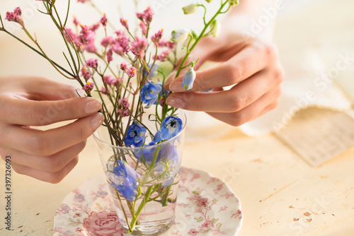 Hispanic woman arranging flowers in glass cup photo