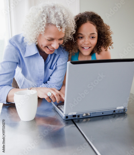 Grandmother and granddaughter using laptop photo