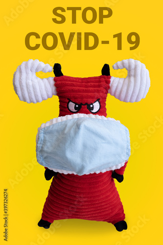 Bull symbol of 2021 in a medical mask on a yellow background. the inscription stop coronavirus