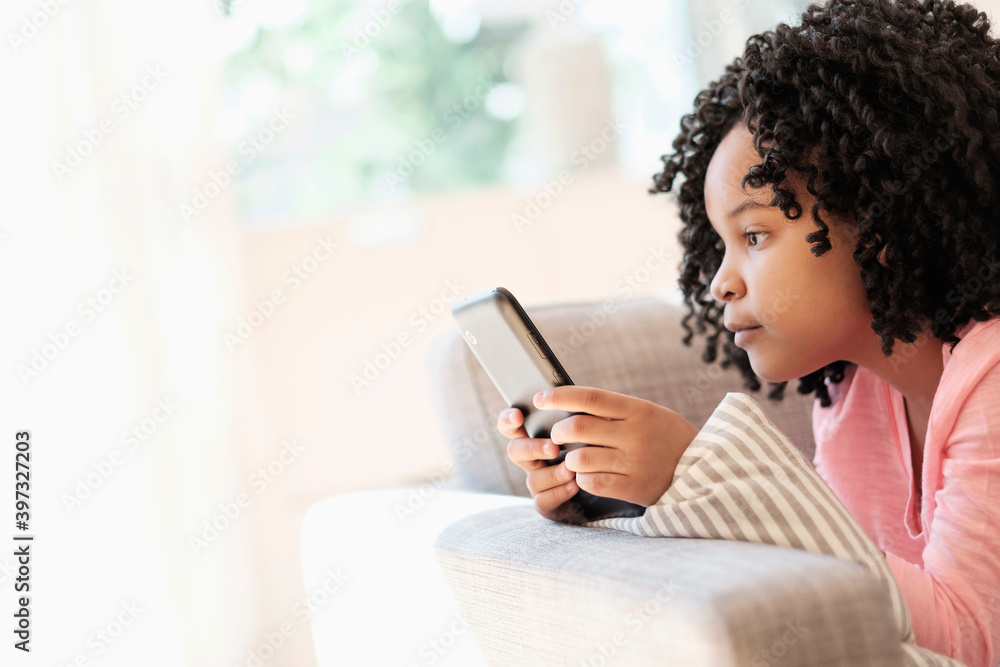 African American girl using cell phone on sofa African American girl using cell phone on sofa