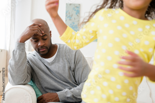 Daughter playing while father has headache photo