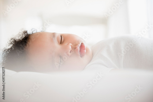 Mixed Race baby boy sleeping on bed