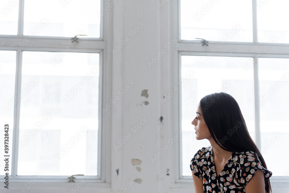 Pensive Indian woman sitting near window Pensive Indian woman sitting near window