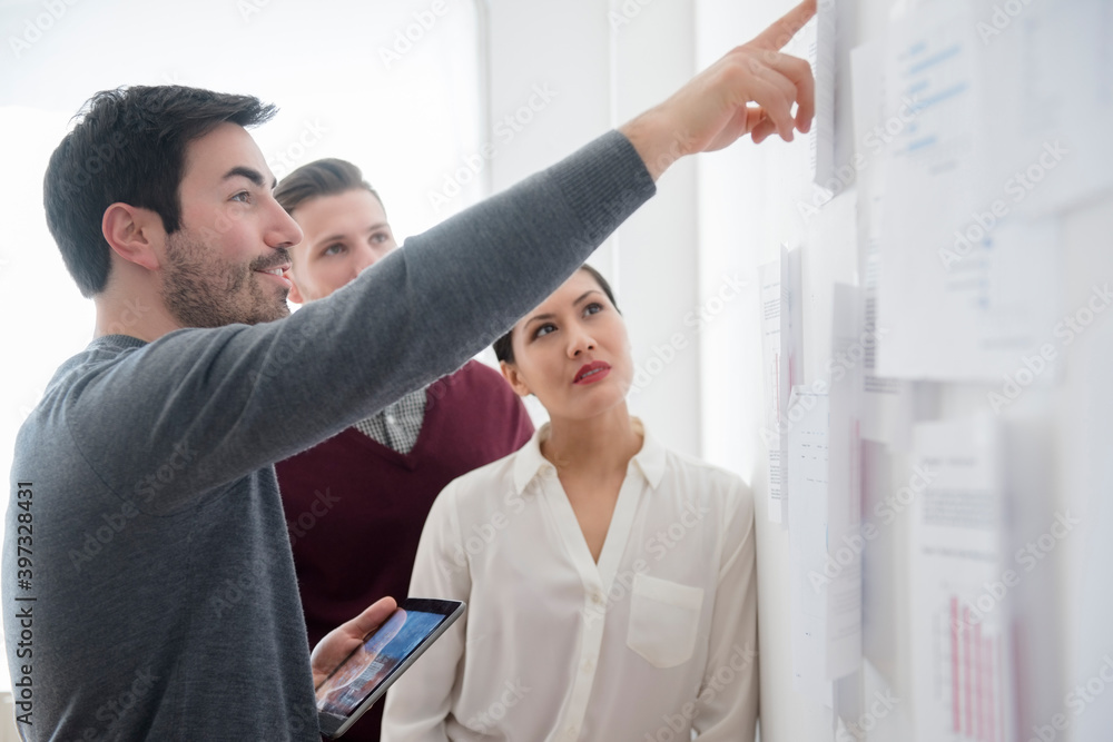 Business people talking about paperwork on wall Business people talking about paperwork on wall