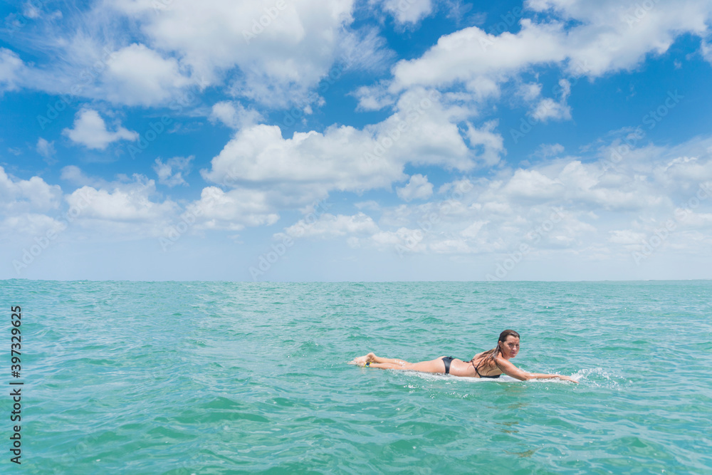 Caucasian woman paddling on surfboard in ocean
