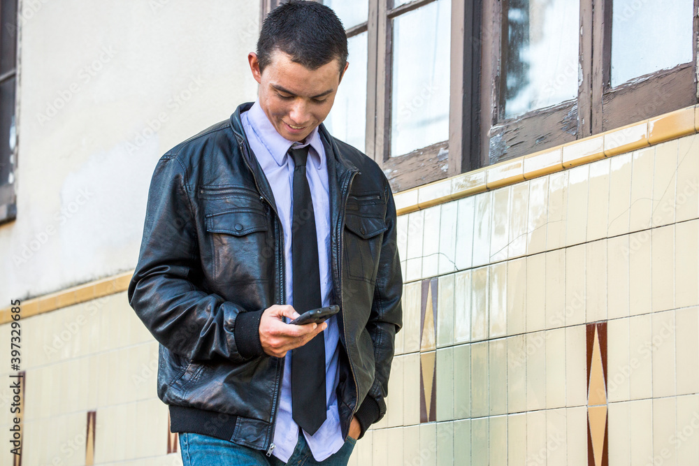 Mixed Race man wearing leather jacket texting on cell phone Mixed Race man wearing leather jacket texting on cell phone
