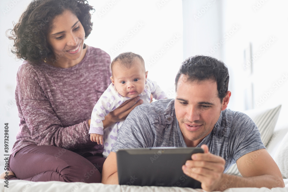 Hispanic mother and father with baby daughter watching digital tablet Hispanic mother and father with baby daughter watching digital tablet