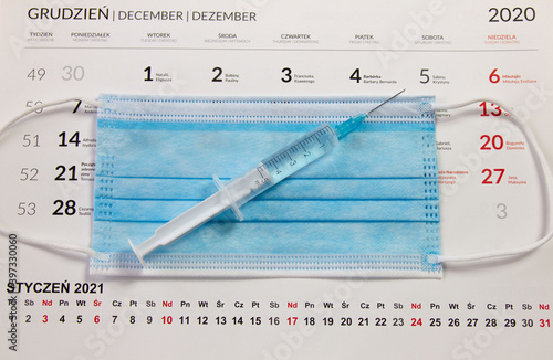 Kalendarz, maseczka chirurgiczna i strzykawka. Motyw terminu szczepienia przeciwko wirusowi Covid-19

 photo