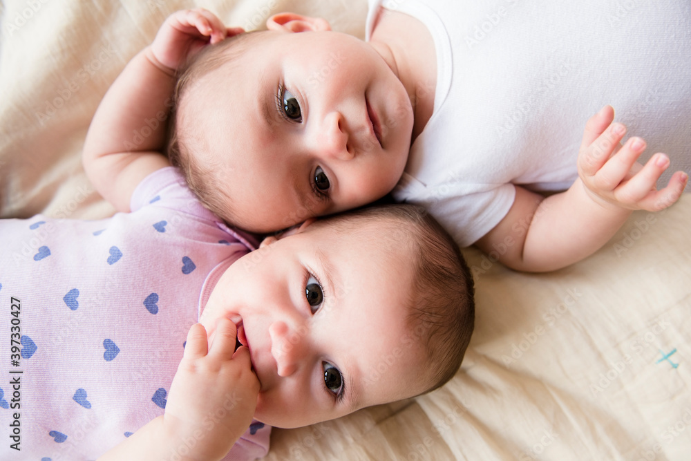 Caucasian twin baby girls laying on bed Caucasian twin baby girls laying on bed