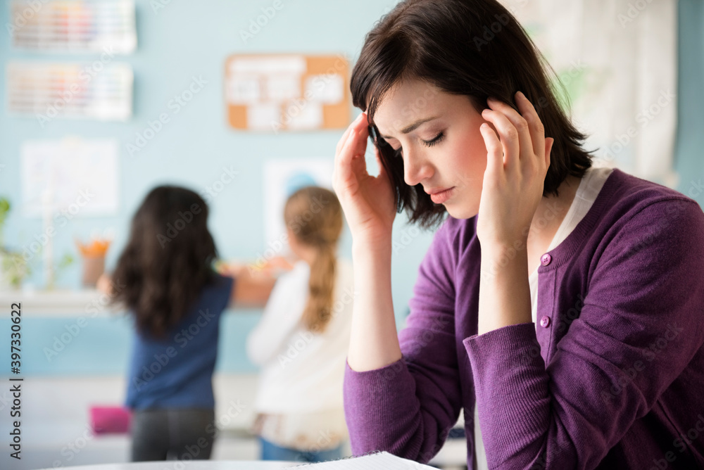 Caucasian teacher with headache in classroom Caucasian teacher with headache in classroom