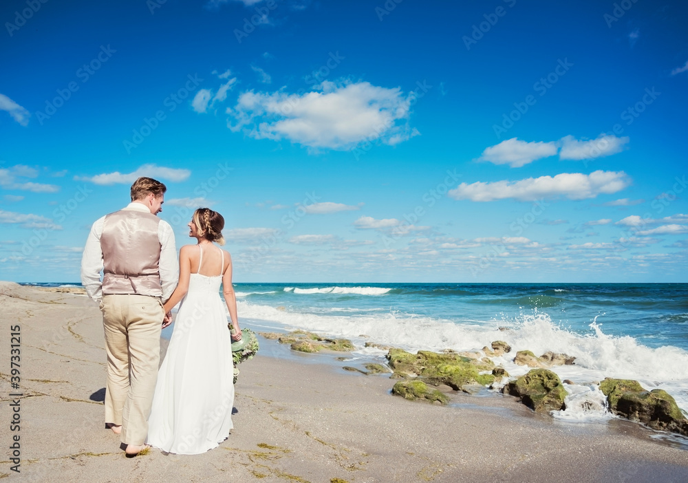 Caucasian bride and groom walking on beach Caucasian bride and groom walking on beach