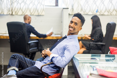 Portrait of smiling Black man relaxing in office photo