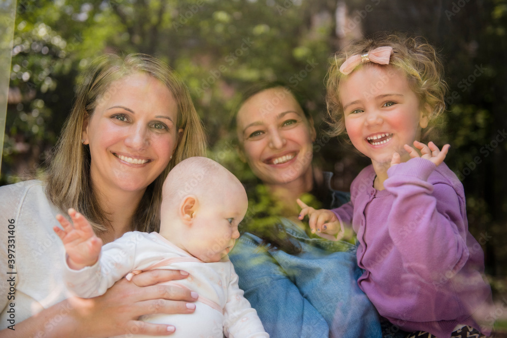 Caucasian mothers and daughters waving behind window Caucasian mothers and daughters waving behind window