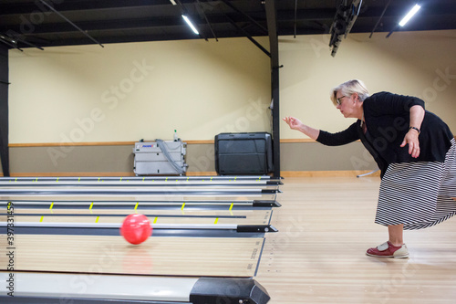 Caucasian woman releasing bowling ball in lane photo