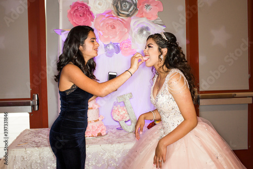 Hispanic girl feeding cookie to friend photo