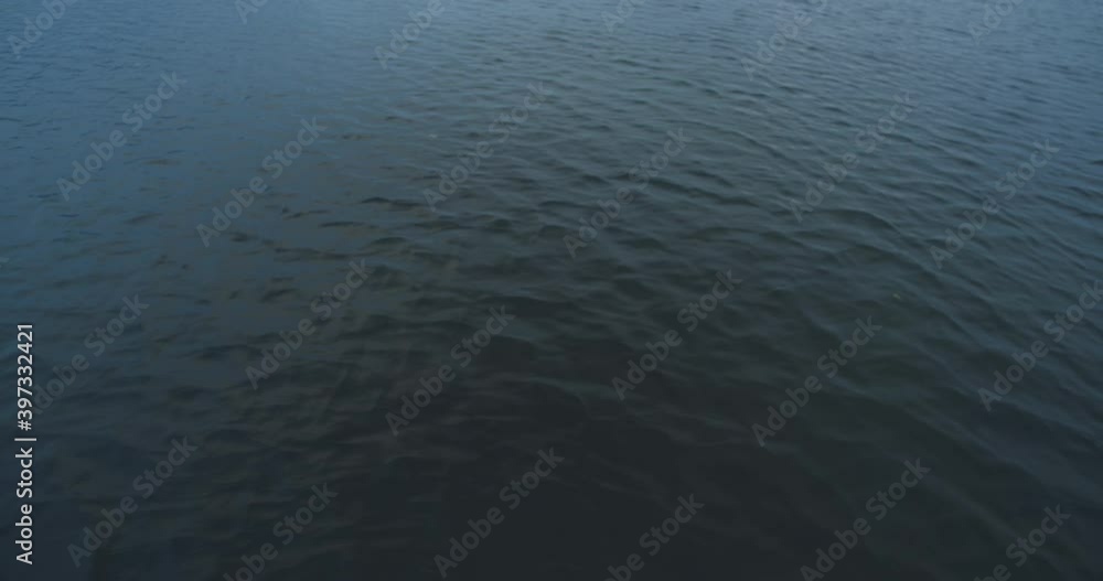 The wind is forming waves and reflections with the mist and light of a cold sunrise during winter on lake Mondsee, Austria The wind is forming waves and reflections with the mist and light of a cold sunrise during winter on lake Mondsee, Austria
